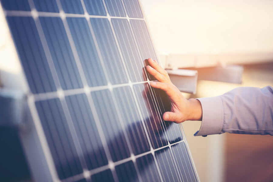 Nahaufnahme der Hand einer Person, die ein Solarpanel berührt, ein Symbol für saubere Energie, Nachhaltigkeit und moderne erneuerbare Technologie.
