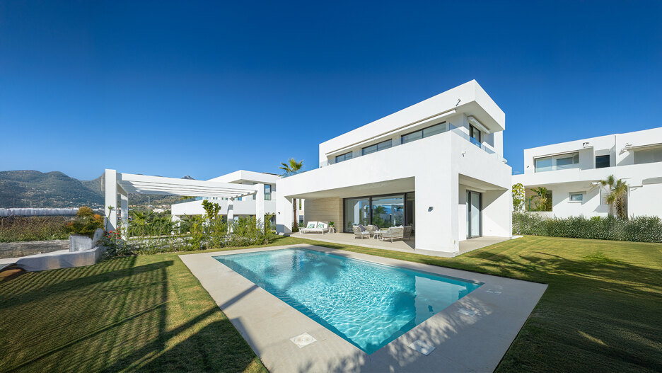 Moderne Villa mit privatem Pool, gepflegtem Garten und Bergblick unter klarem blauen Himmel in Marbella.