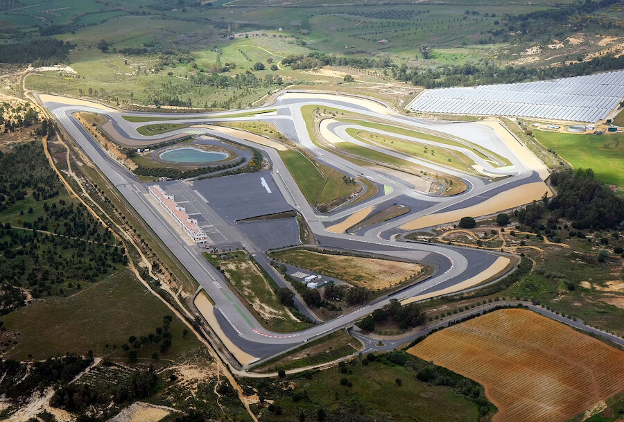 Luftaufnahme des Circuito Monteblanco, einer modernen Rennstrecke mit zahlreichen technischen Kurven, langen Geraden, Boxengebäuden und umliegenden grünen Feldern in einer ländlichen Gegend.