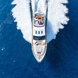 Luchtfoto van een luxe jacht dat met hoge snelheid door de diepblauwe zee vaart en een witte kielzog achterlaat.