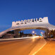 Iconic Marbella entrance arch illuminated at dusk, with traffic lights creating motion trails on the main coastal road