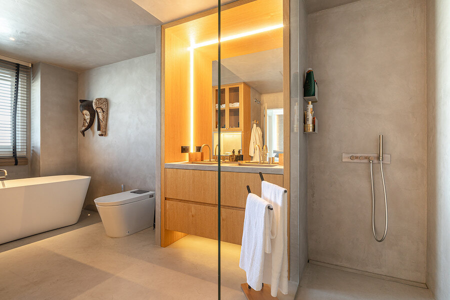 Modernes Luxusbad mit freistehender Badewanne, begehbarer Dusche, Waschtisch aus Holz und eleganter Beleuchtung.