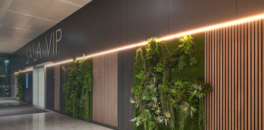Entrance to the VIP lounge at Málaga Airport, featuring vertical gardens and modern wooden panel accents along the wall.