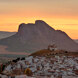 Zonsondergang boven de Peña de los Enamorados in Antequera, met het menselijke gezicht van de rots en het witgekalkte stadje op de voorgrond.