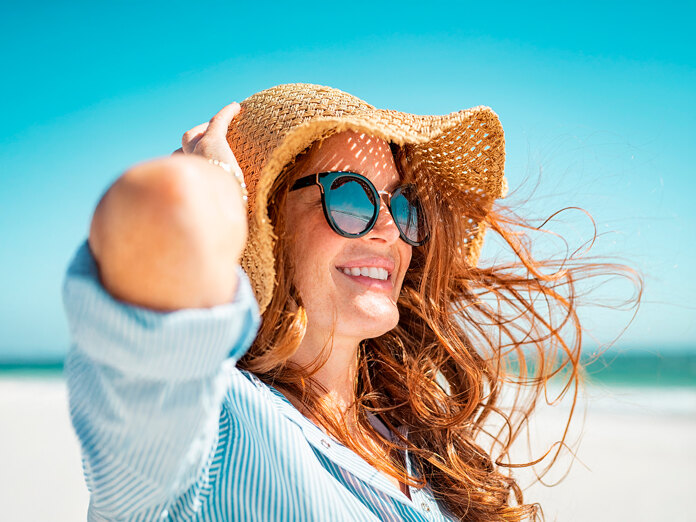 How Moving to Marbella Can Improve Your Health. Woman enjoying the sun on the beach.