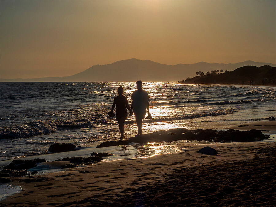 Paar geht bei Sonnenuntergang am Strand in Marbella spazieren.