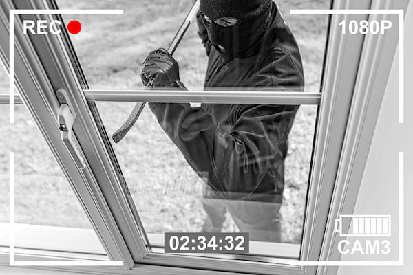 Home insurance. Photos from a security recording of a burglar trying to break into a house through a window to steal something.