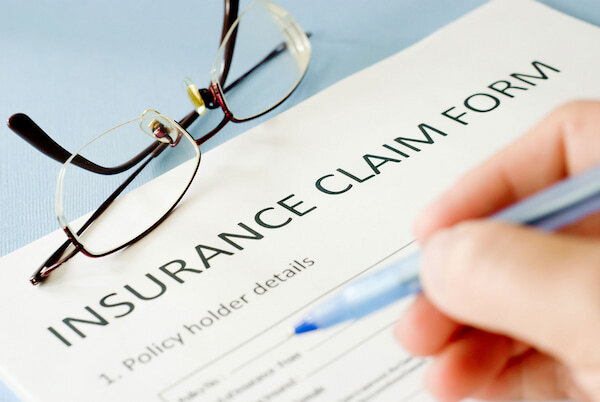 Insurance claim form Woman's hand holding a pen with which she is filling out a home insurance claim form.