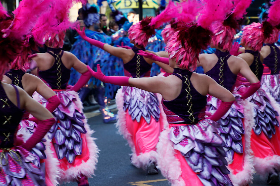 Défilé de femmes au Carnaval de Malaga. Les femmes portent une robe et un chapeau extravagant avec des plumes.