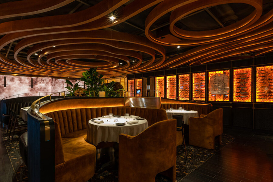 Elegant interior of Leña restaurant with curved wooden ceiling design, warm lighting, and round dining tables.